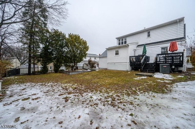 snow covered house featuring central AC and a wooden deck