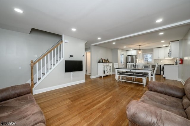 living area with stairs, baseboards, wood finished floors, and recessed lighting