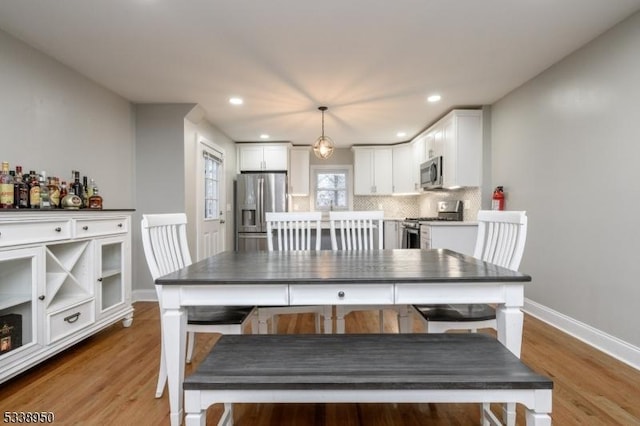 dining area with baseboards, wood finished floors, and recessed lighting