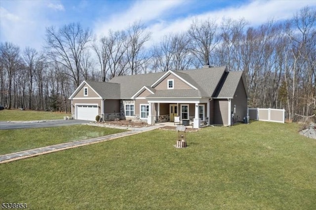 craftsman house with driveway, an attached garage, fence, a front lawn, and a porch