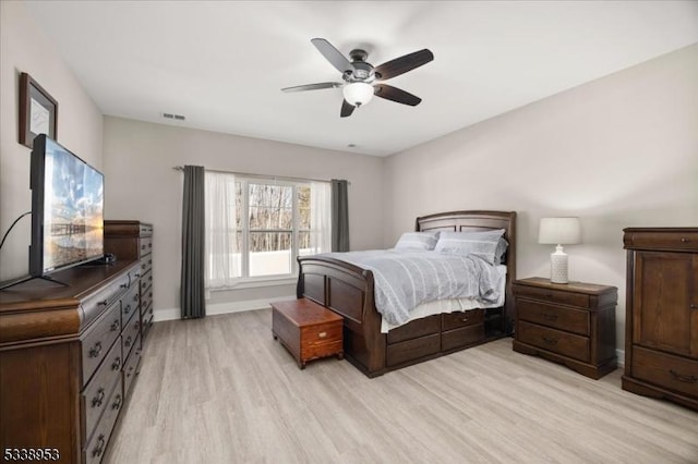 bedroom with baseboards, light wood-type flooring, visible vents, and a ceiling fan