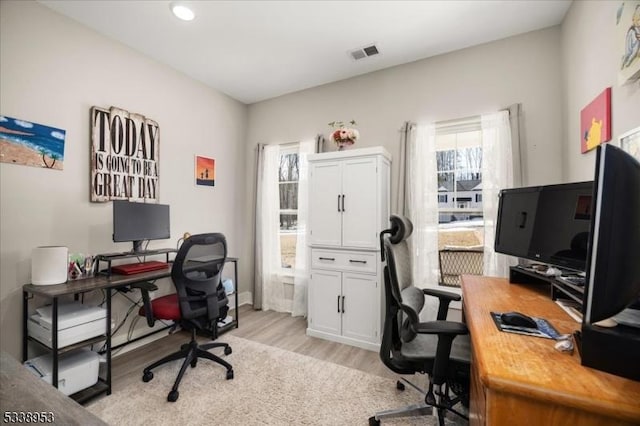 office with light wood-style flooring and visible vents