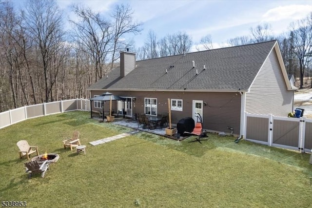 rear view of house with a lawn, a gazebo, a gate, a patio area, and a fire pit