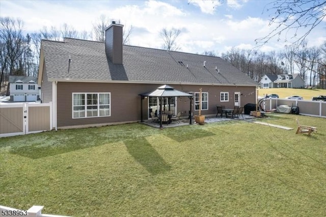 rear view of property featuring roof with shingles, a patio, a chimney, and fence