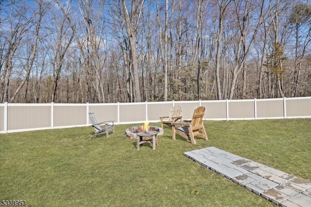 view of yard with an outdoor fire pit, a fenced backyard, and a view of trees