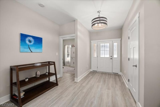 foyer with light wood-type flooring, an inviting chandelier, and baseboards