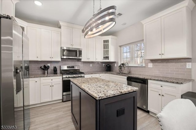 kitchen with stainless steel appliances, backsplash, light wood-style flooring, and white cabinets