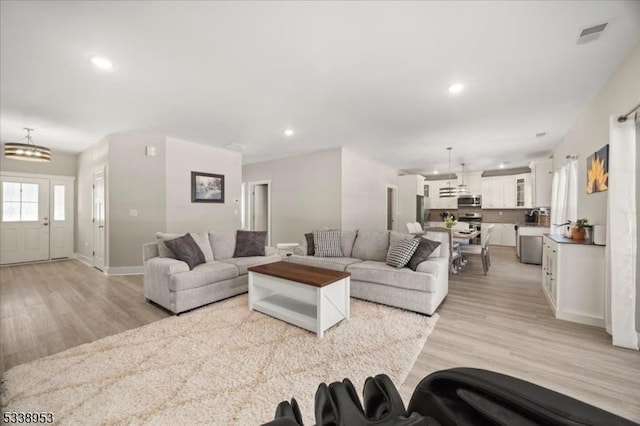 living area with recessed lighting, baseboards, visible vents, and light wood finished floors