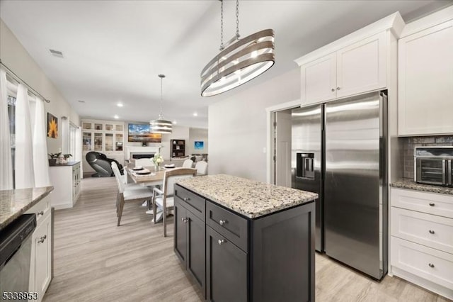 kitchen featuring stainless steel fridge, visible vents, dishwashing machine, a fireplace, and white cabinetry