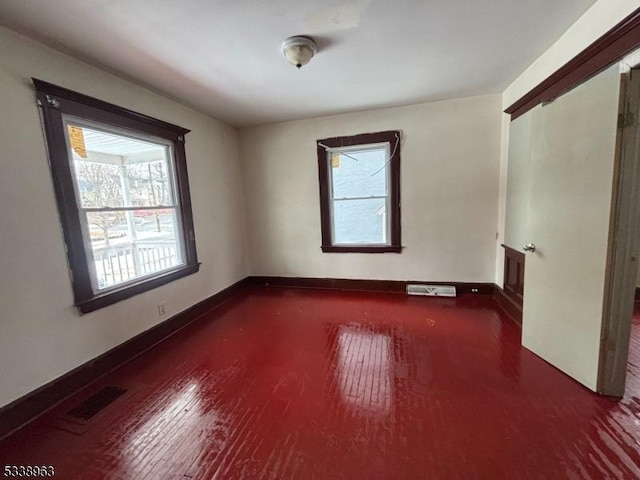 spare room with dark hardwood / wood-style flooring and a wealth of natural light