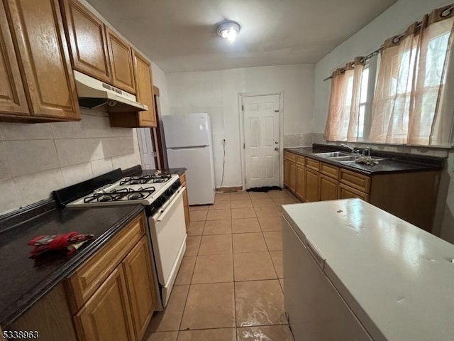 kitchen featuring white appliances, light tile patterned flooring, sink, and backsplash