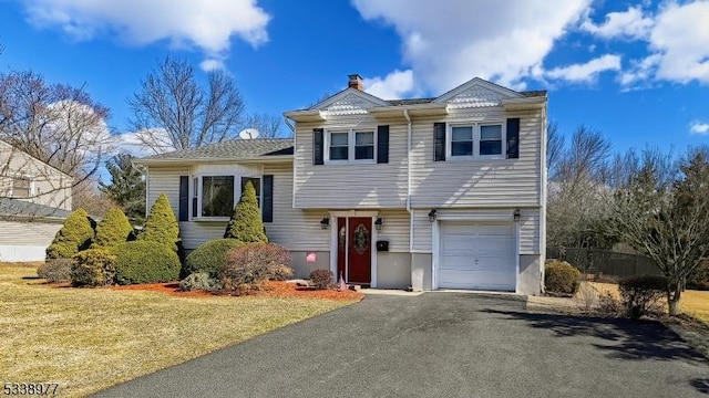 split level home featuring aphalt driveway, an attached garage, and a front yard