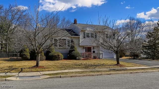 tri-level home with a garage, a front lawn, a chimney, and driveway