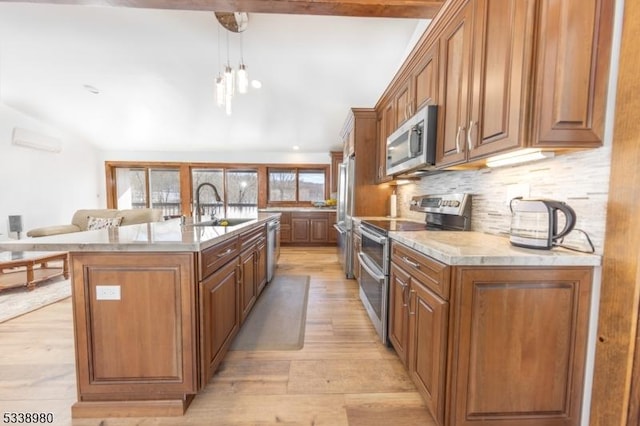 kitchen featuring brown cabinetry, an island with sink, appliances with stainless steel finishes, light countertops, and a sink