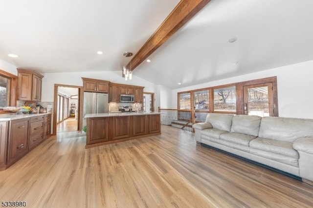 kitchen featuring lofted ceiling with beams, stainless steel appliances, open floor plan, light countertops, and brown cabinetry