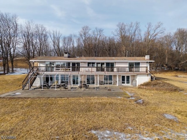 back of house featuring a yard, a patio, a chimney, a deck, and stairs