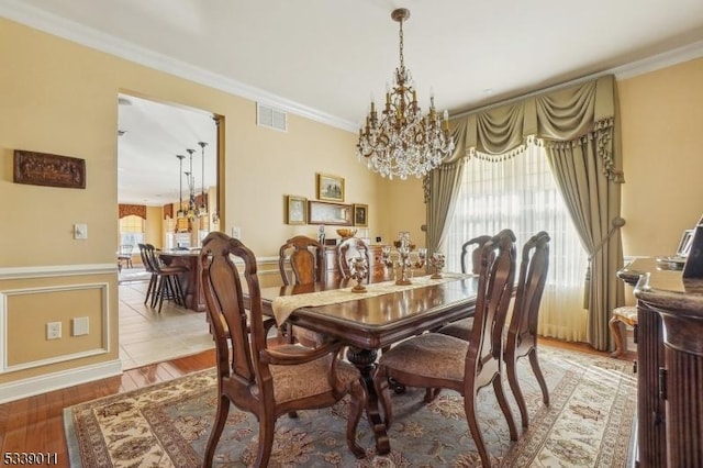 dining room with an inviting chandelier, wood-type flooring, and ornamental molding