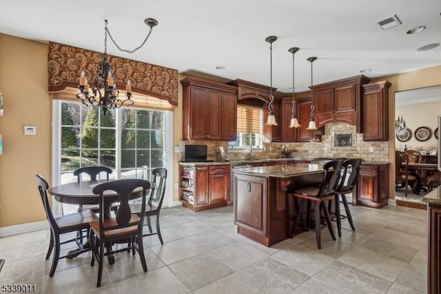 kitchen with decorative light fixtures, tasteful backsplash, an inviting chandelier, and a center island