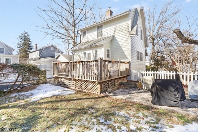 snow covered rear of property featuring fence, a chimney, and a wooden deck