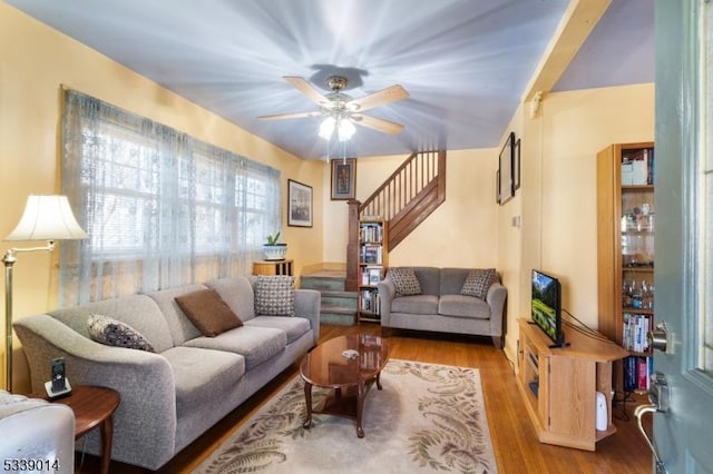 living area featuring ceiling fan, stairway, and wood finished floors