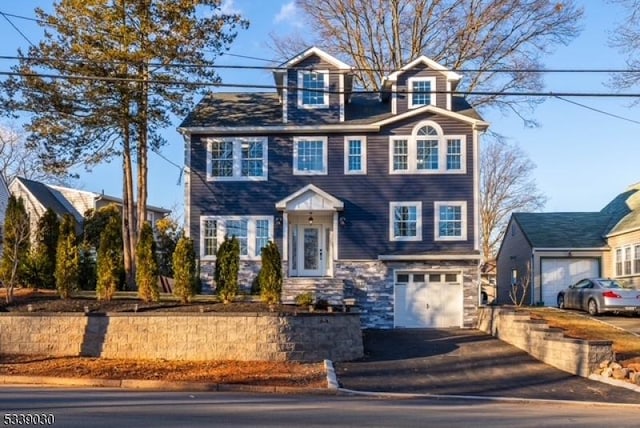 view of front of home featuring a garage, stone siding, and driveway