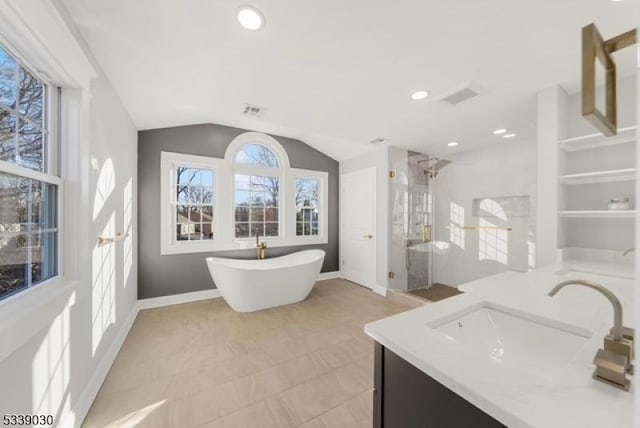 bathroom featuring a freestanding tub, visible vents, baseboards, vaulted ceiling, and a stall shower