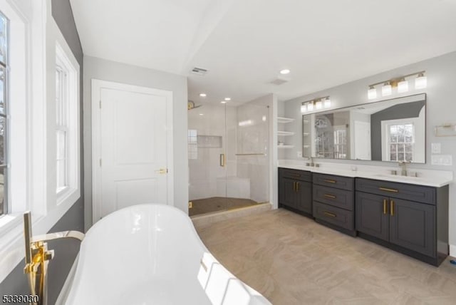 bathroom with a stall shower, a sink, a freestanding bath, and double vanity