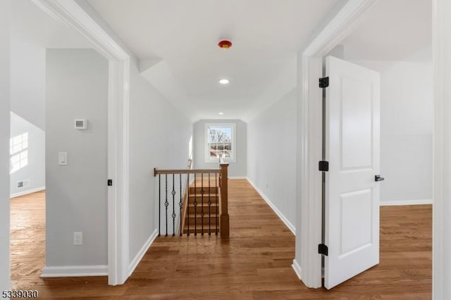 hallway with baseboards, an upstairs landing, and wood finished floors