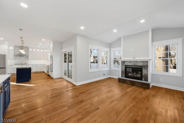 living area with vaulted ceiling, a fireplace, and light wood finished floors