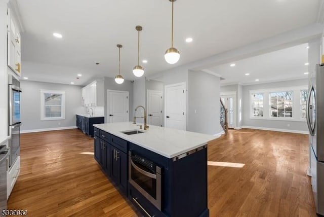 kitchen with white cabinets, wood finished floors, blue cabinets, a sink, and recessed lighting