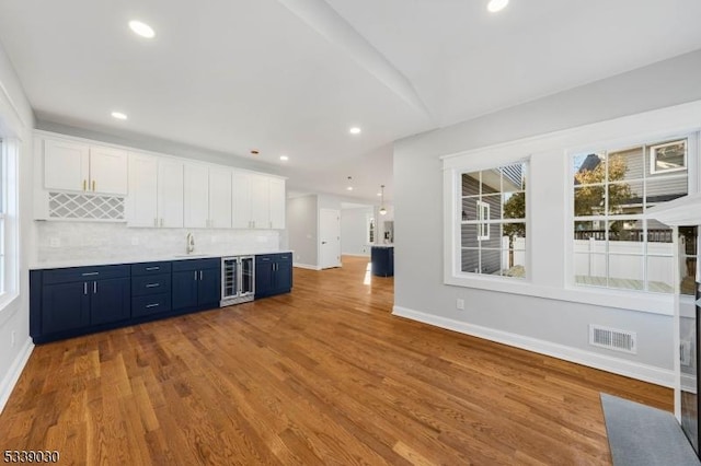 kitchen with beverage cooler, visible vents, blue cabinetry, and wood finished floors