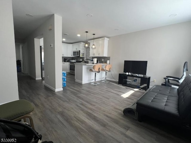 living room featuring dark wood-type flooring, recessed lighting, and baseboards