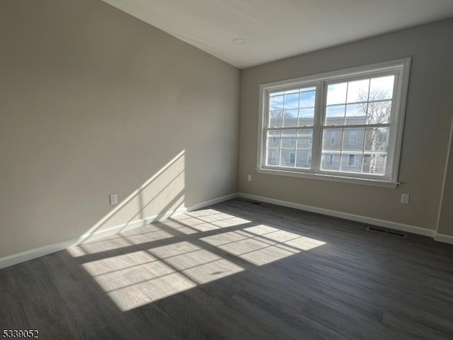 unfurnished room featuring wood finished floors, visible vents, and baseboards