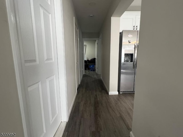 corridor featuring baseboards and dark wood-style flooring