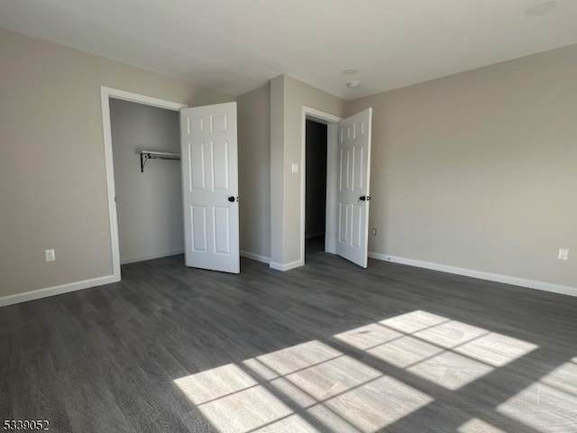 unfurnished bedroom featuring a closet, dark wood-style flooring, and baseboards