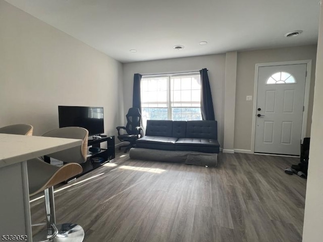 living area with baseboards, visible vents, and dark wood-type flooring