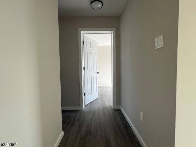 hallway with dark wood-style flooring and baseboards