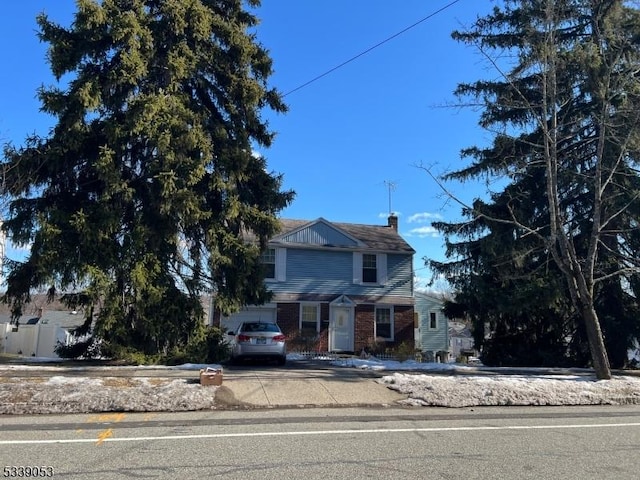 view of front of home featuring brick siding, driveway, and a chimney