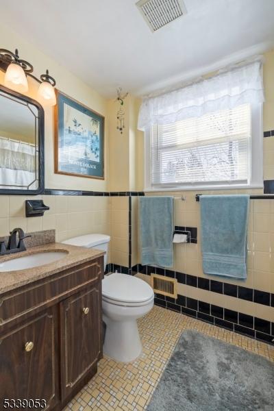 full bath featuring visible vents, toilet, tile patterned floors, vanity, and tile walls