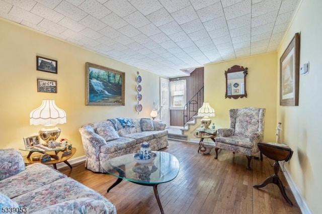 living area with stairs, hardwood / wood-style flooring, and baseboards