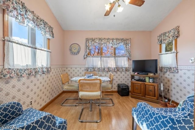 interior space with lofted ceiling, wainscoting, wood finished floors, and wallpapered walls