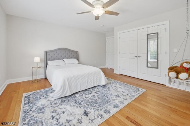 bedroom featuring a ceiling fan, a closet, baseboards, and wood finished floors