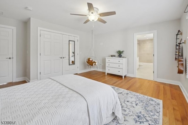 bedroom featuring a closet, ceiling fan, ensuite bath, light wood-type flooring, and baseboards