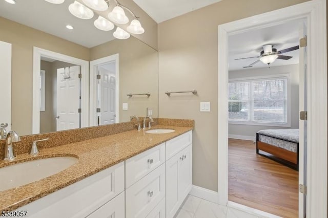 bathroom with marble finish floor, a sink, baseboards, and double vanity