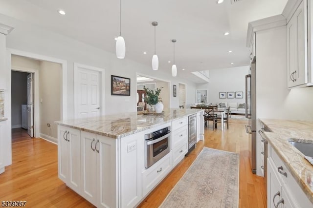 kitchen with appliances with stainless steel finishes, beverage cooler, white cabinets, and a kitchen island