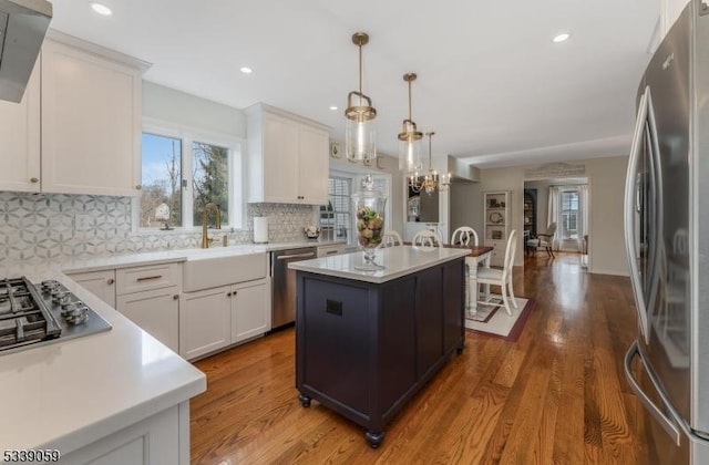 kitchen featuring appliances with stainless steel finishes, white cabinets, light countertops, and a kitchen island