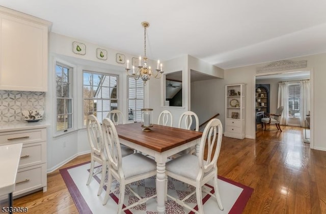 dining room with a healthy amount of sunlight, light wood-style floors, baseboards, and a notable chandelier