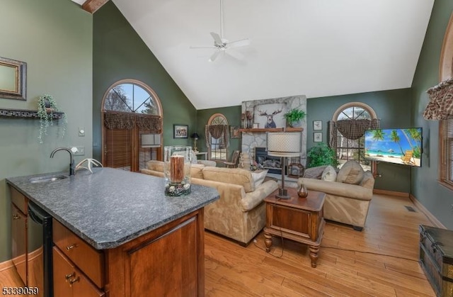 living room with a fireplace, light wood-style floors, ceiling fan, high vaulted ceiling, and baseboards