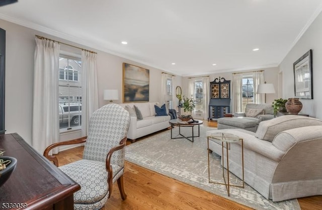 living area with ornamental molding, wood finished floors, and recessed lighting