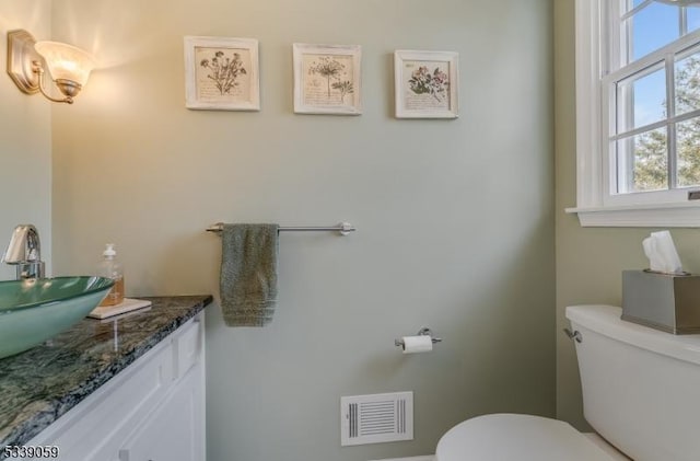 half bath with visible vents, vanity, and toilet